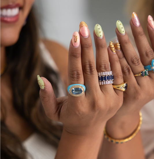 Close-up of hands with various rings and nail polish colors.
