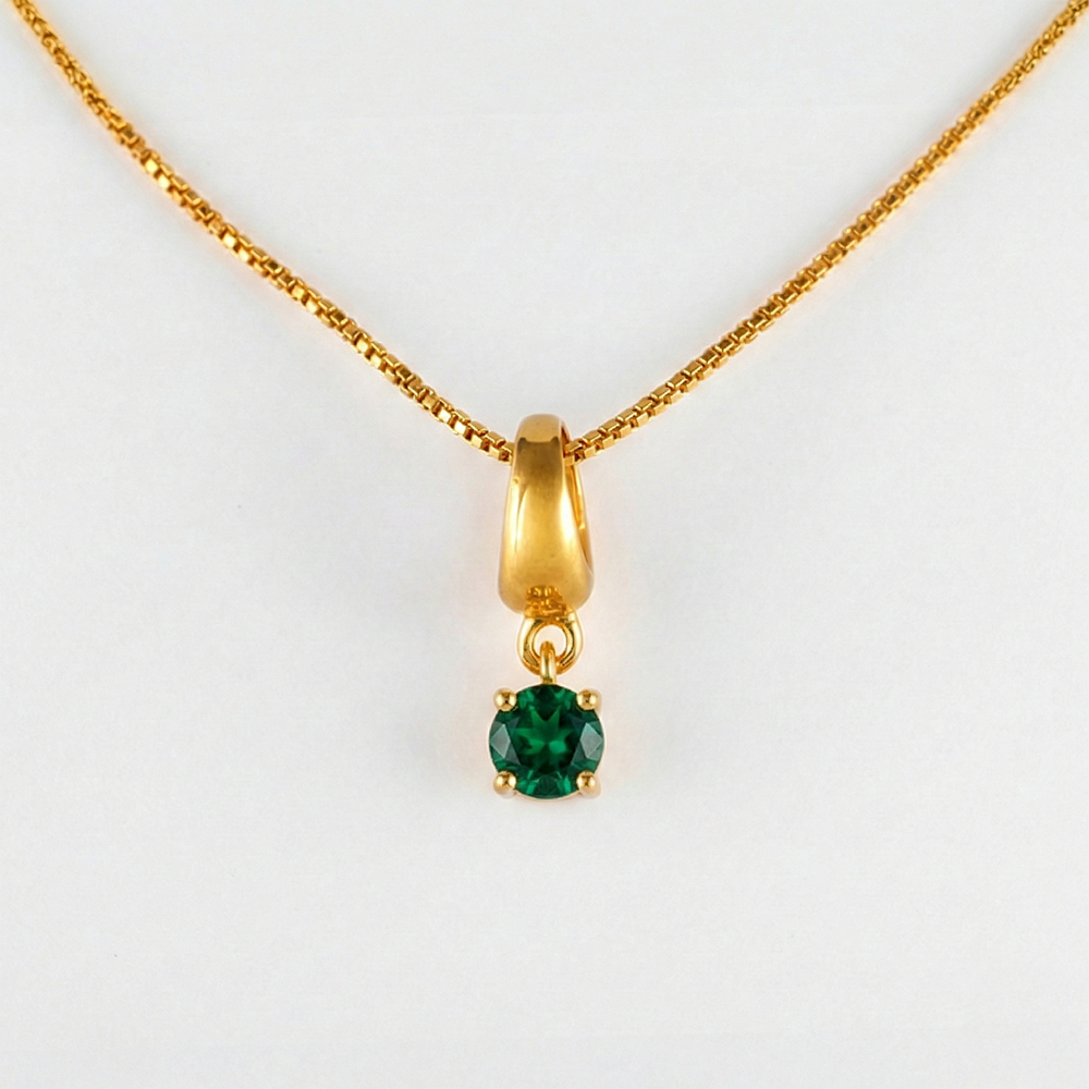 Gold necklace with a green gemstone pendant on a white background