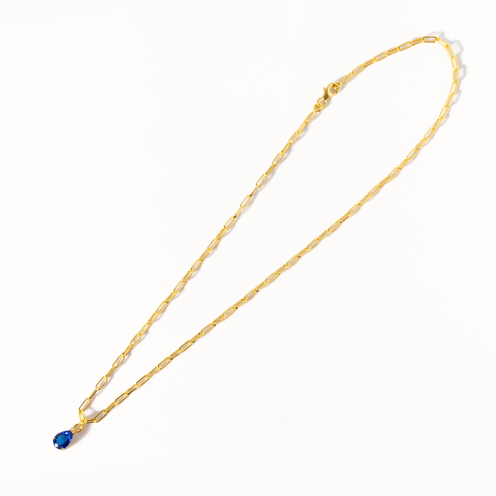 Gold necklace with a blue pendant on a white background