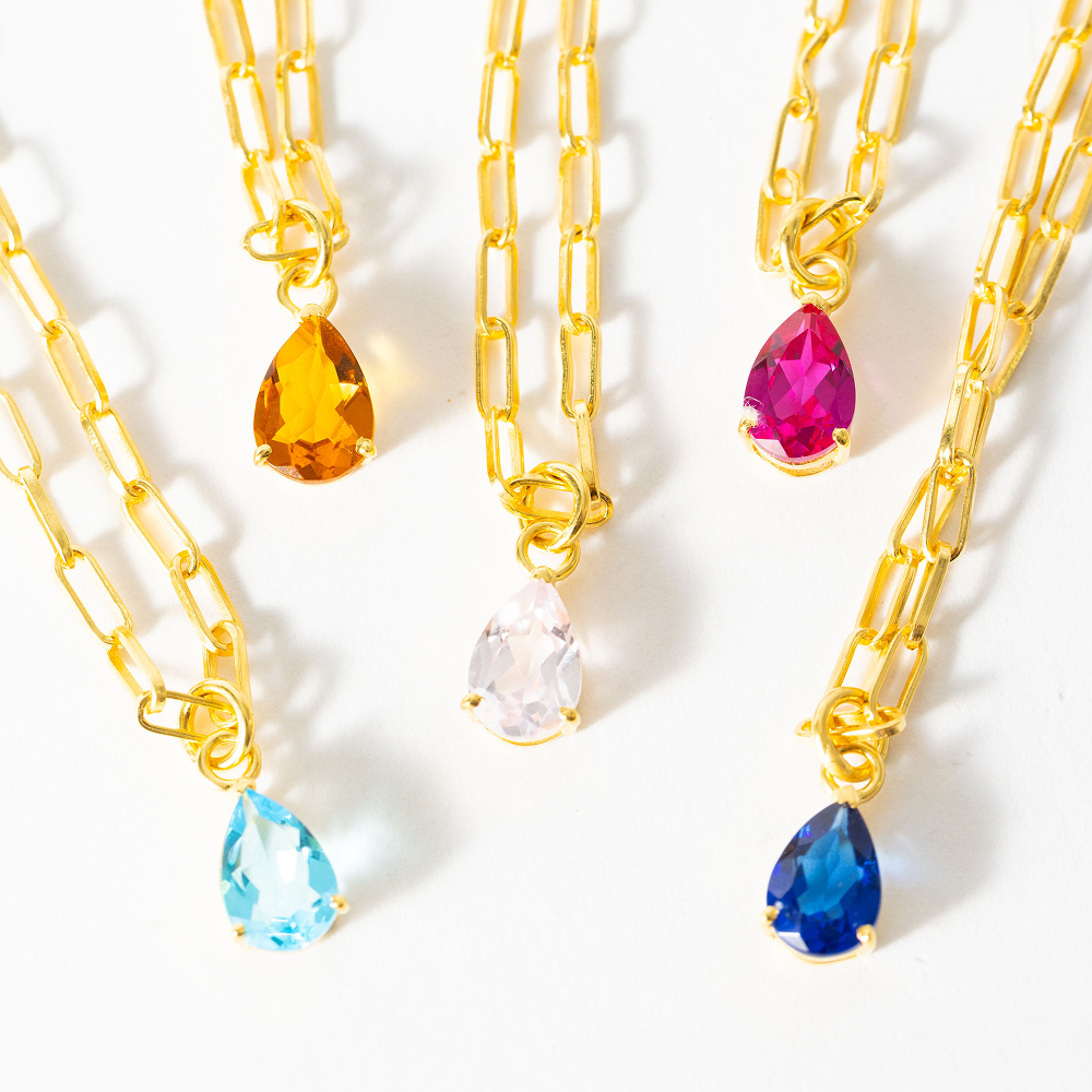 Gold chain necklaces with colorful teardrop pendants on a white background