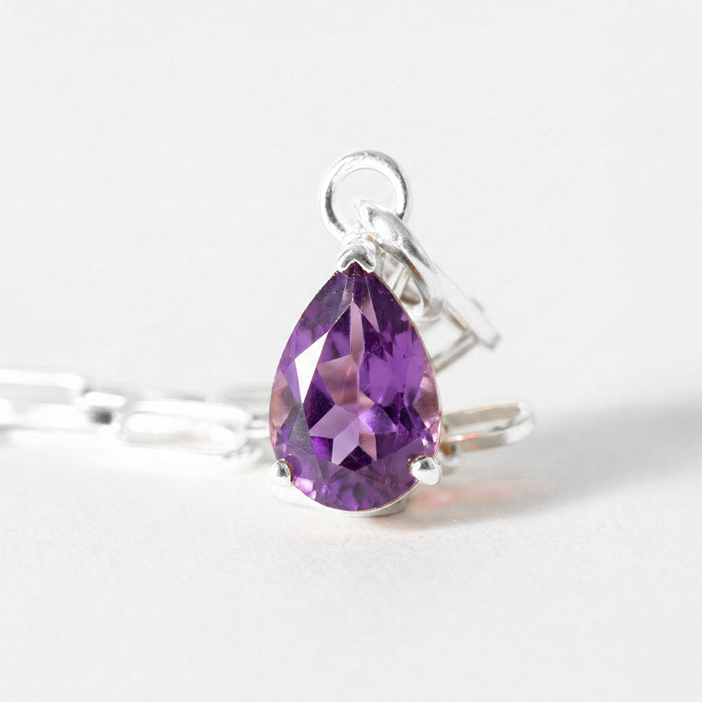 Silver ring with a purple teardrop-shaped gemstone on a white background