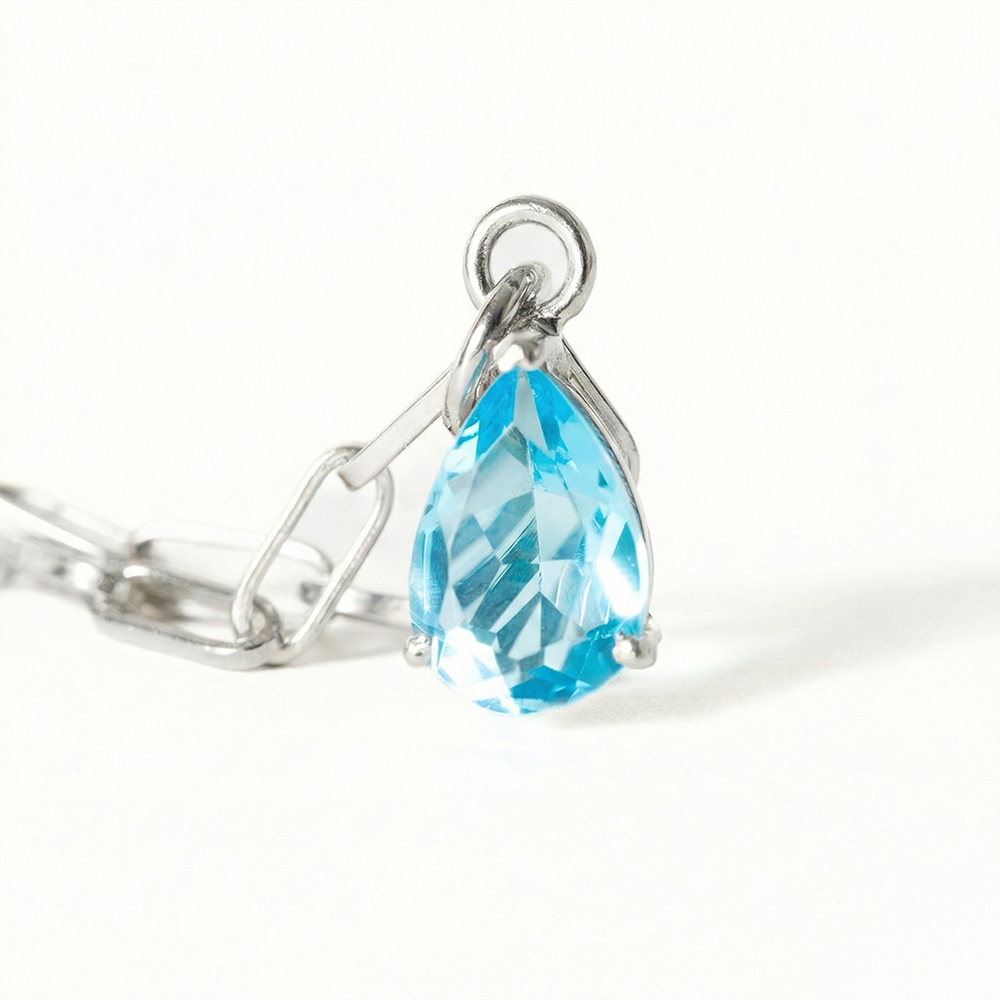 Silver ring with a blue teardrop-shaped gemstone on a white background