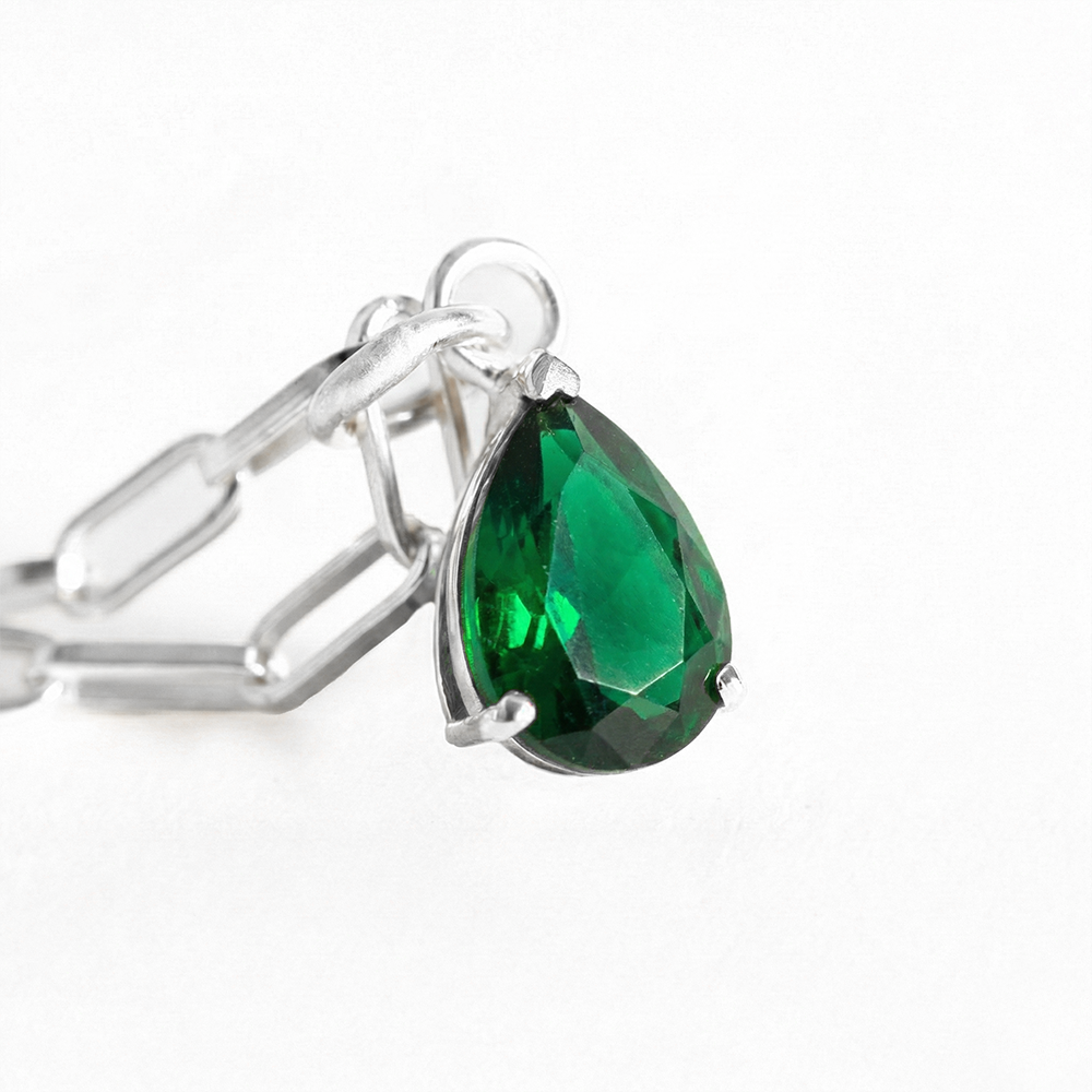 Silver ring with a green teardrop gemstone on a white background