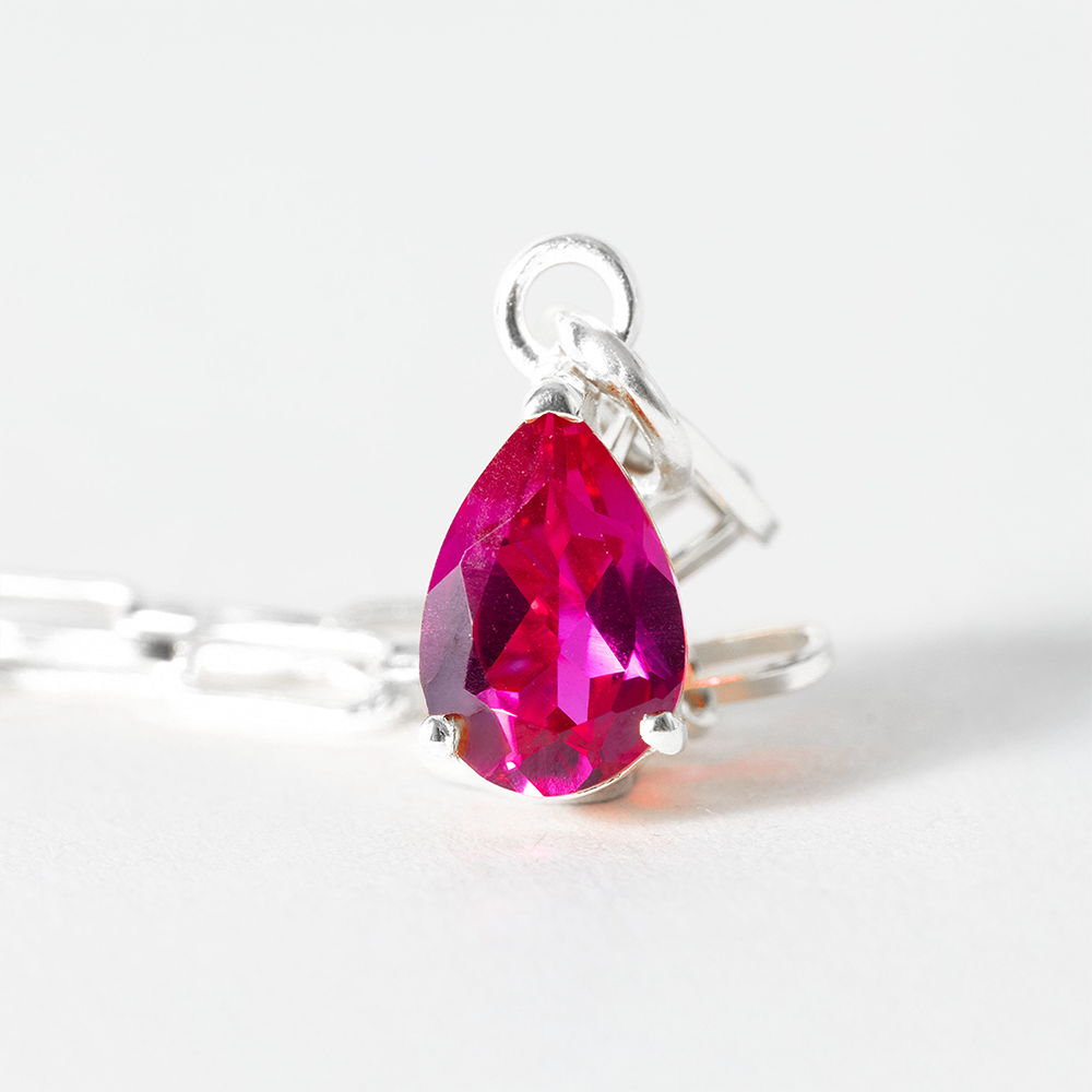 Silver ring with a pink teardrop-shaped gemstone on a white background