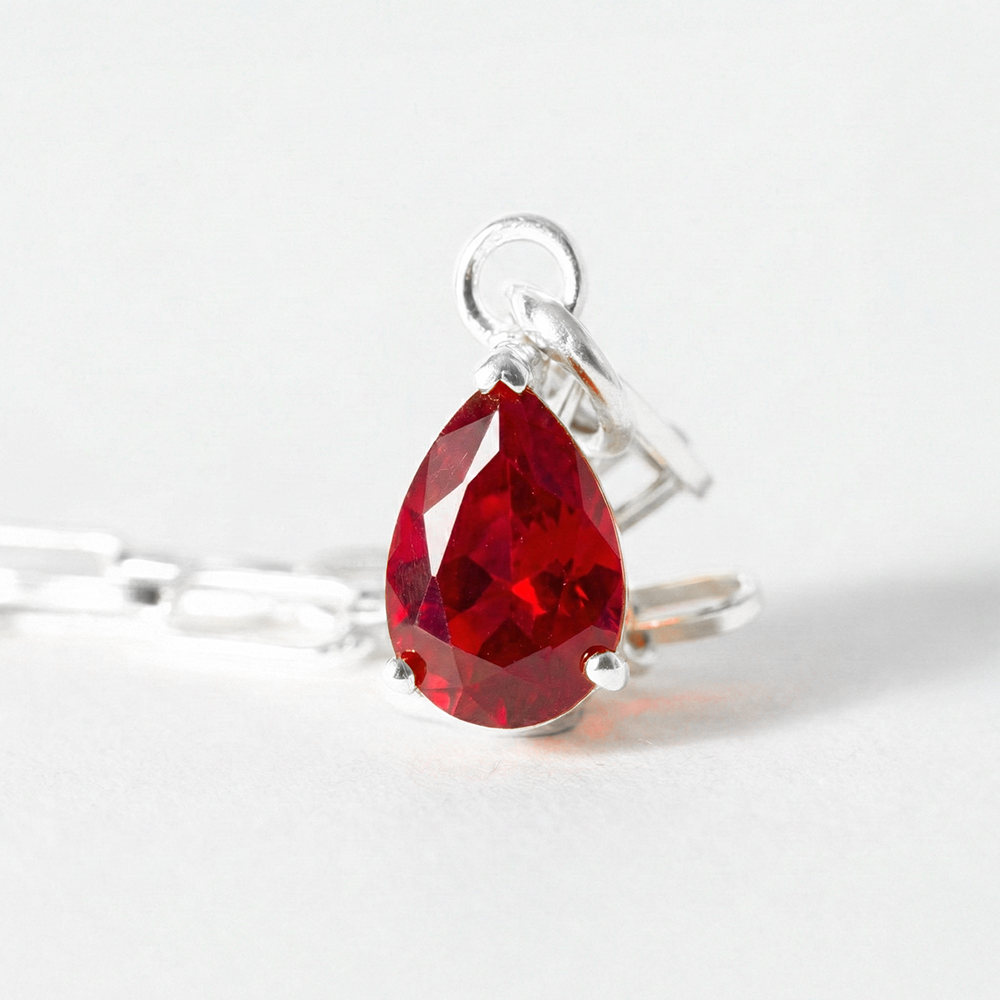 Silver ring with a red teardrop-shaped gemstone on a white background