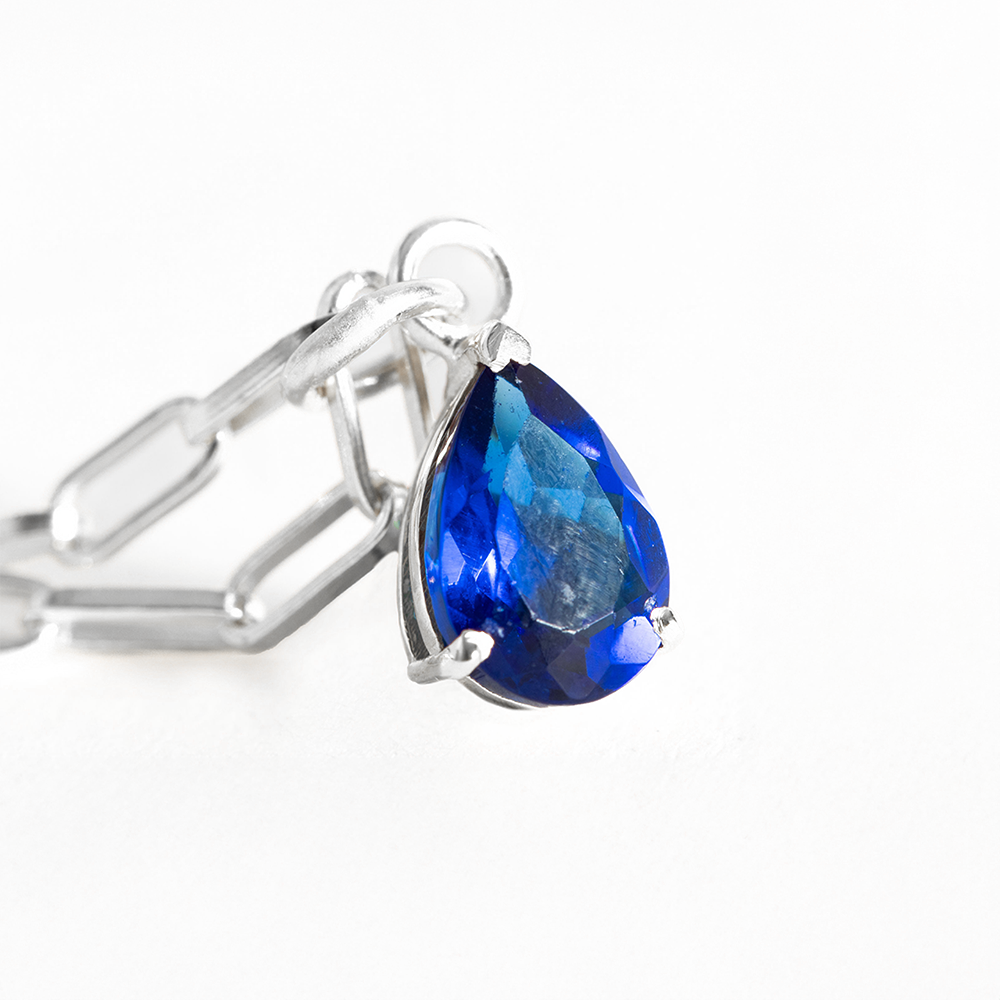 Silver ring with a blue teardrop-shaped gemstone on a white background