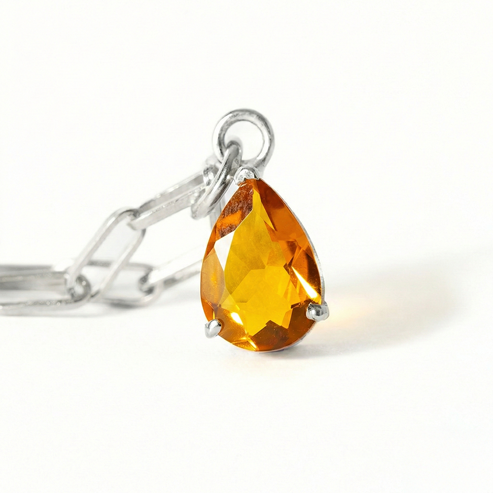 Silver necklace with a teardrop-shaped orange gemstone on a white background