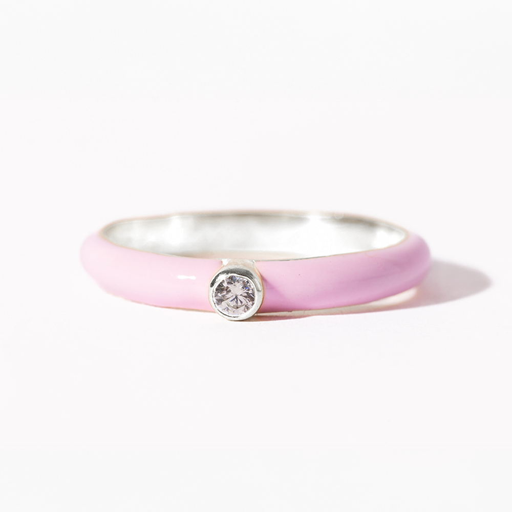 Silver ring with a pink band and central gemstone on a white background