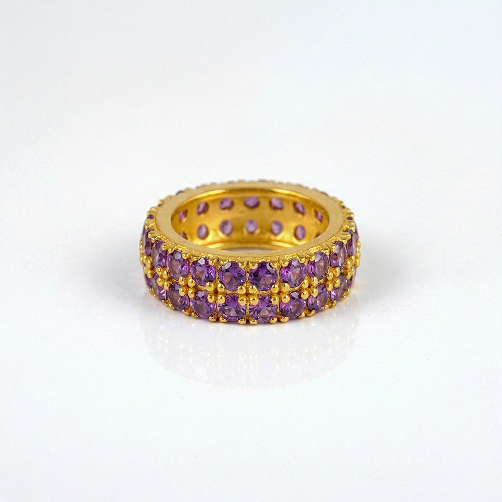 Gold ring with purple gemstones on a white background