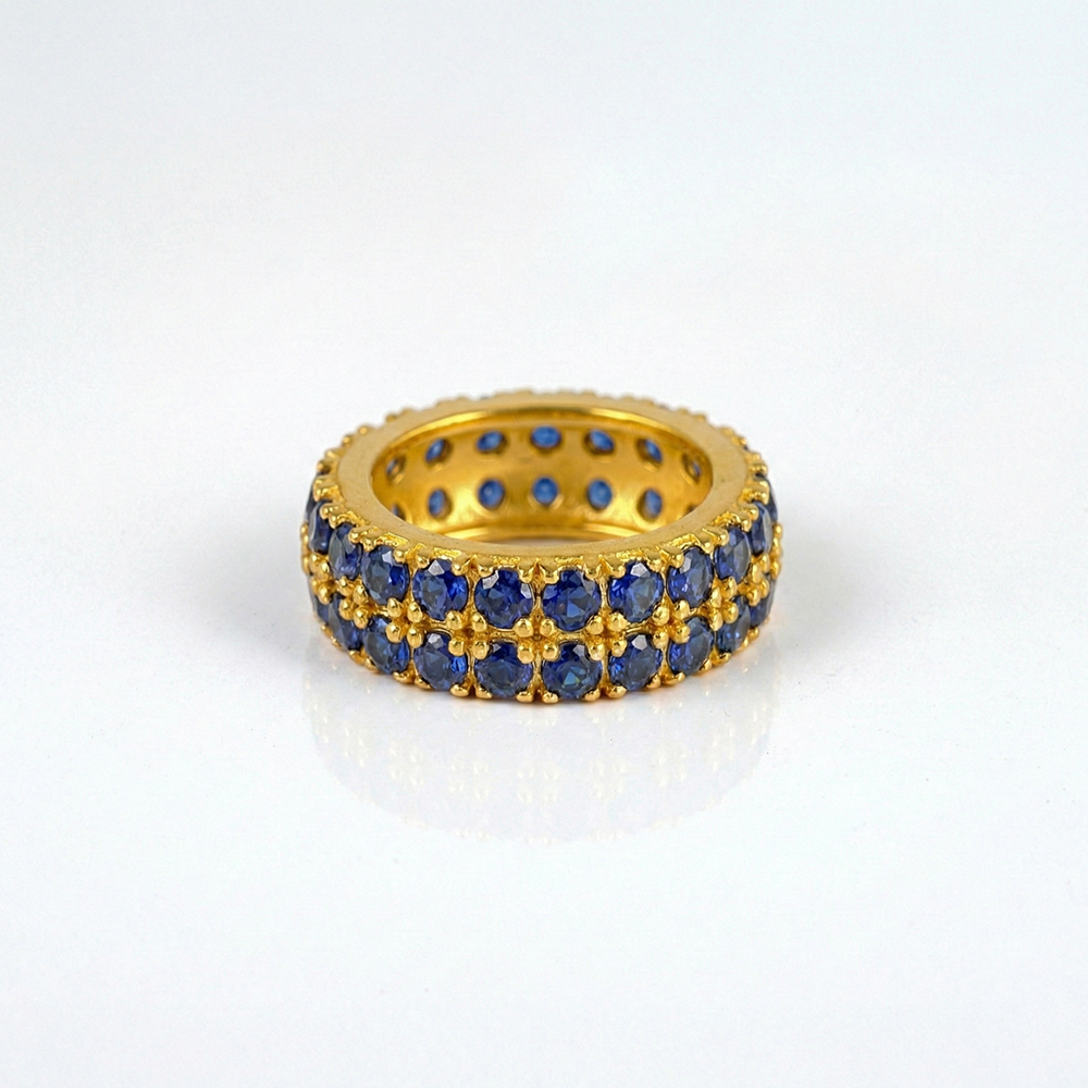 Gold ring with blue gemstones on a white background