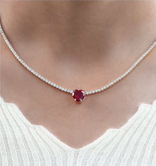 Necklace with a red gemstone and diamond accents worn by a person.