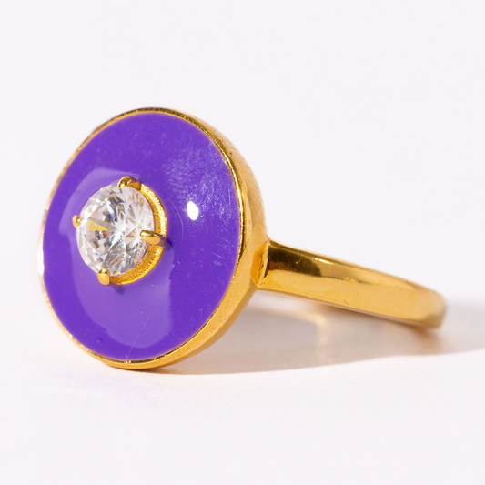 Gold ring with a purple circular stone and clear gemstone on a white background