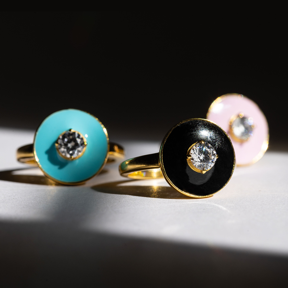 Three rings with colored stones and gold bands on a dark background