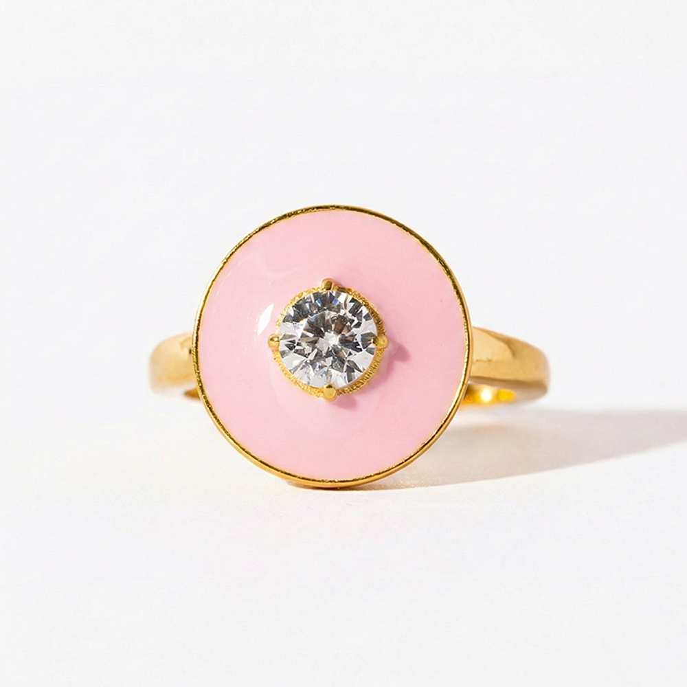 Ring with pink circular stone and gold band on a white background