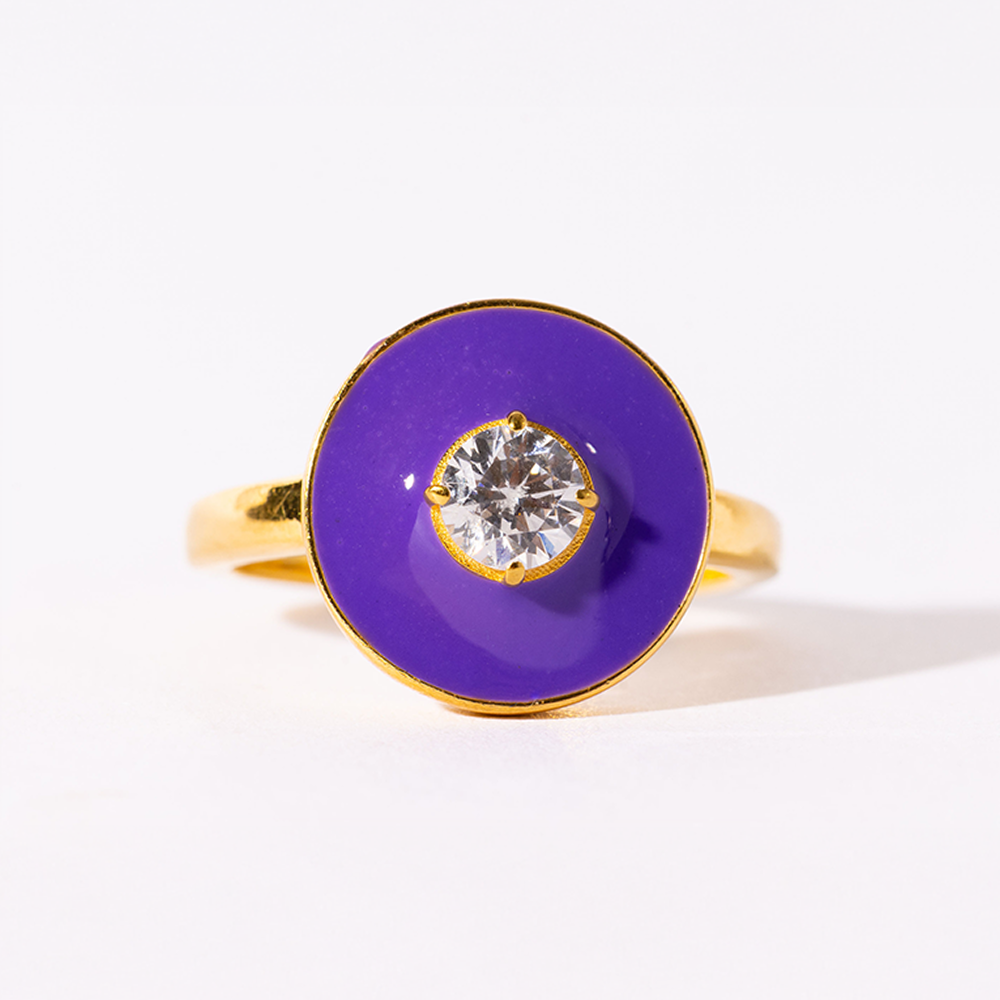 Ring with purple circular stone and gold band on a white background