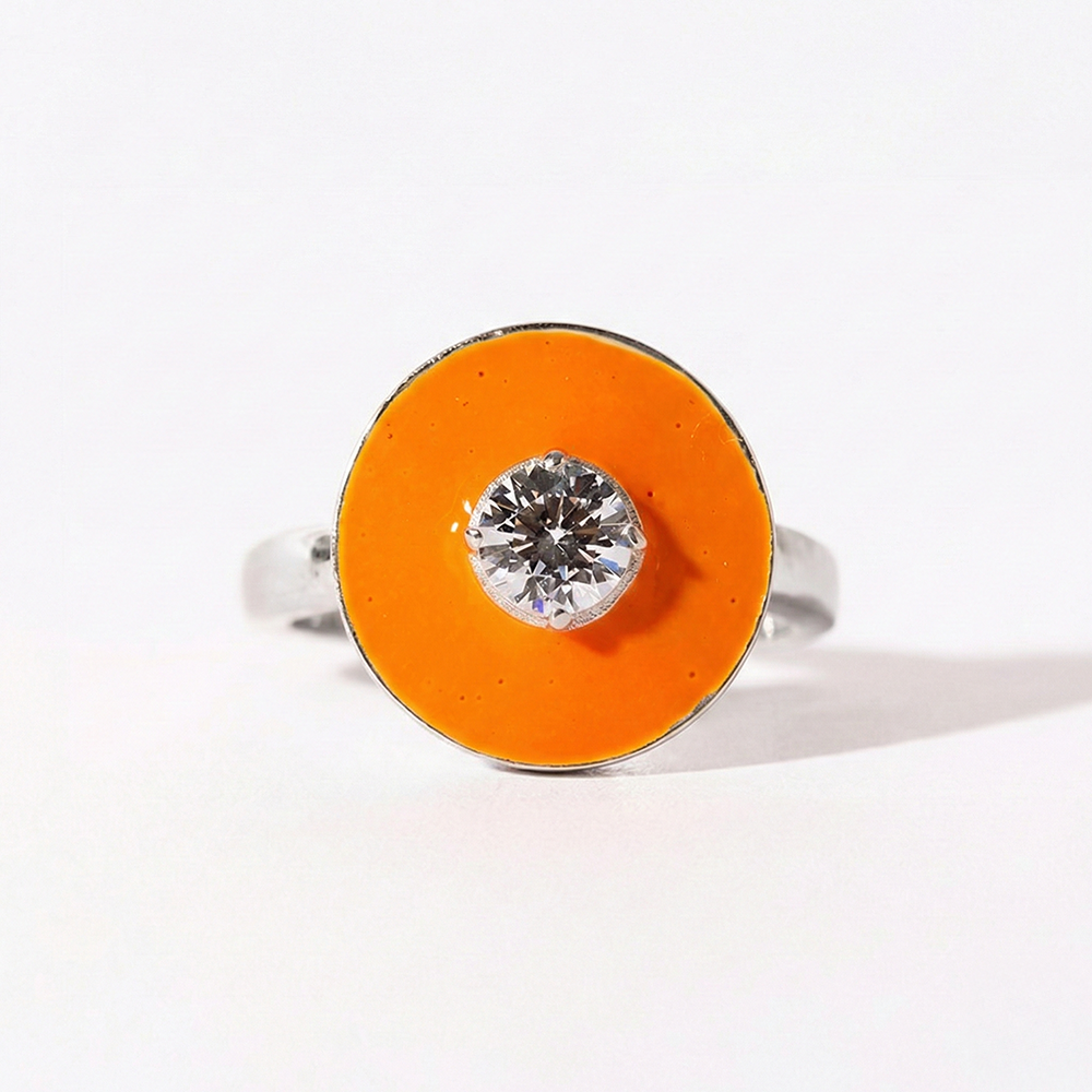 Ring with orange circular stone and silver band on a white background