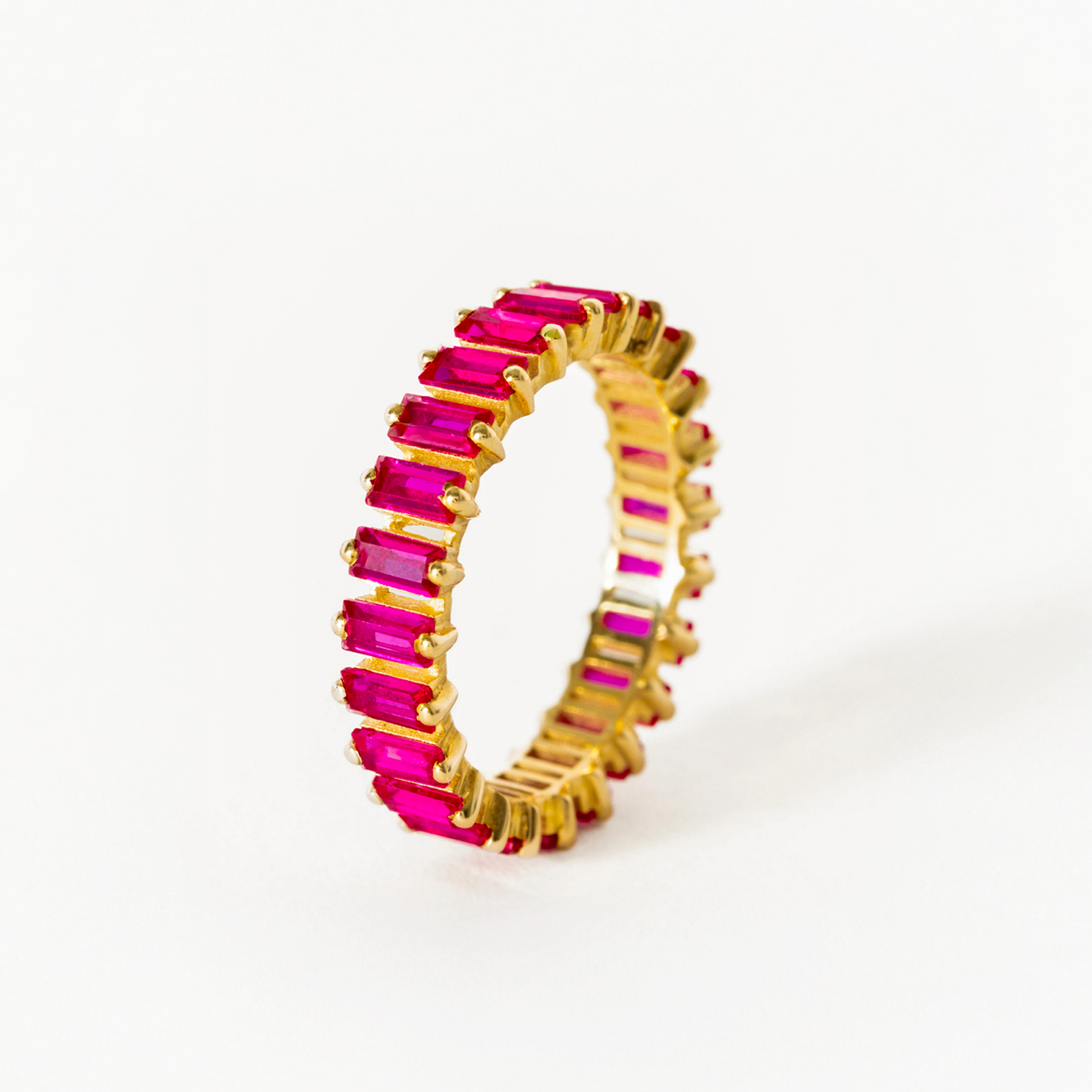Gold ring with pink gemstones on a white background