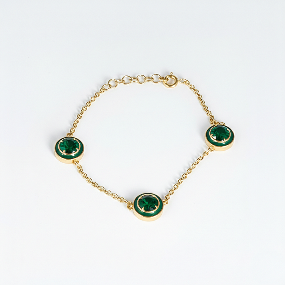 Gold bracelet with green gemstones on a white background