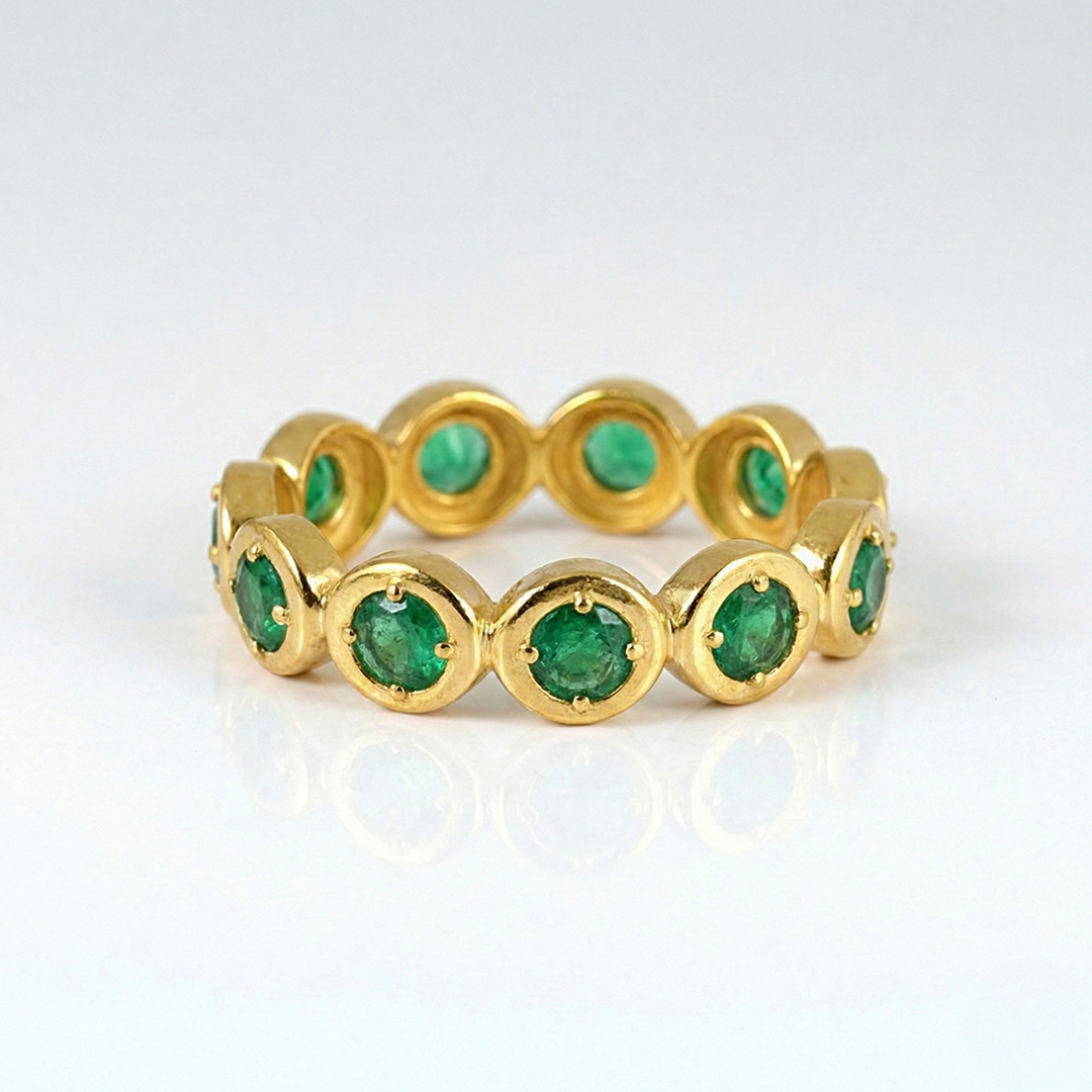 Gold ring with emerald stones on a white background