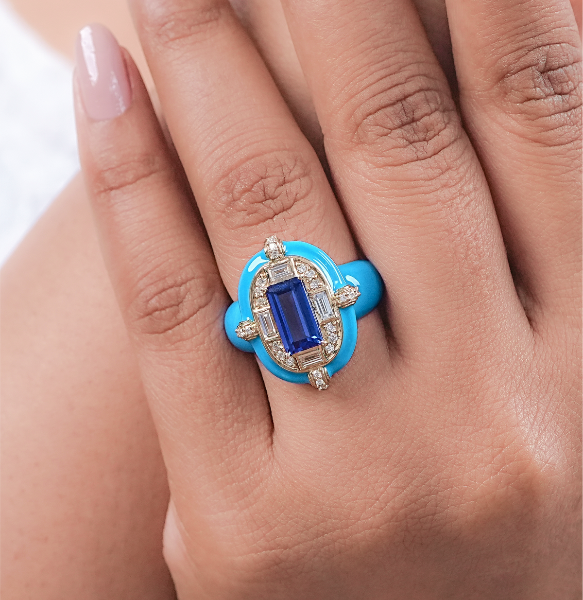 Blue ring with a gemstone on a hand against a white background