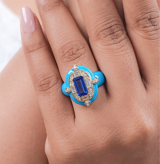 Blue ring with a gemstone on a hand against a white background