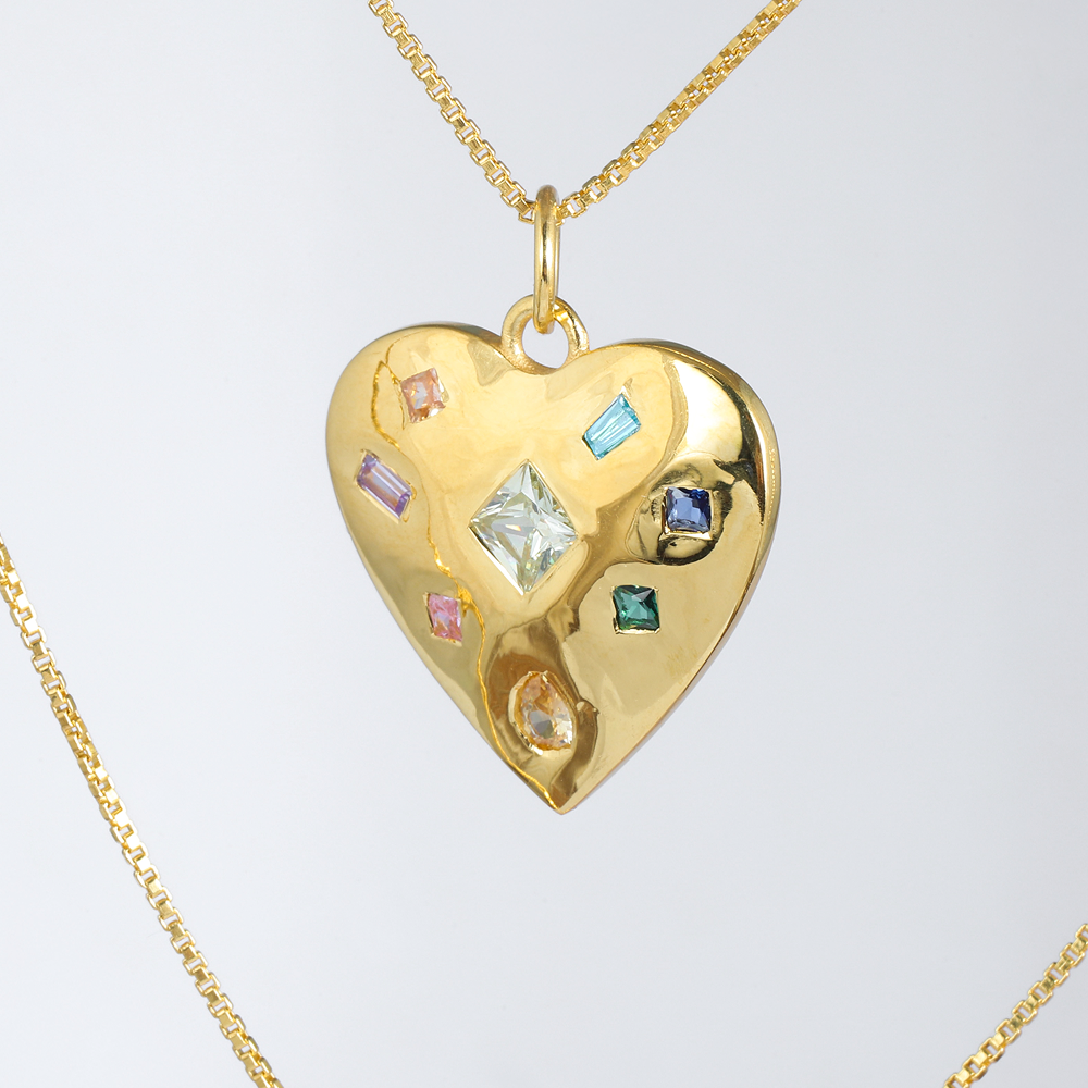 Gold heart-shaped pendant with embedded colorful gemstones on a light gray background
