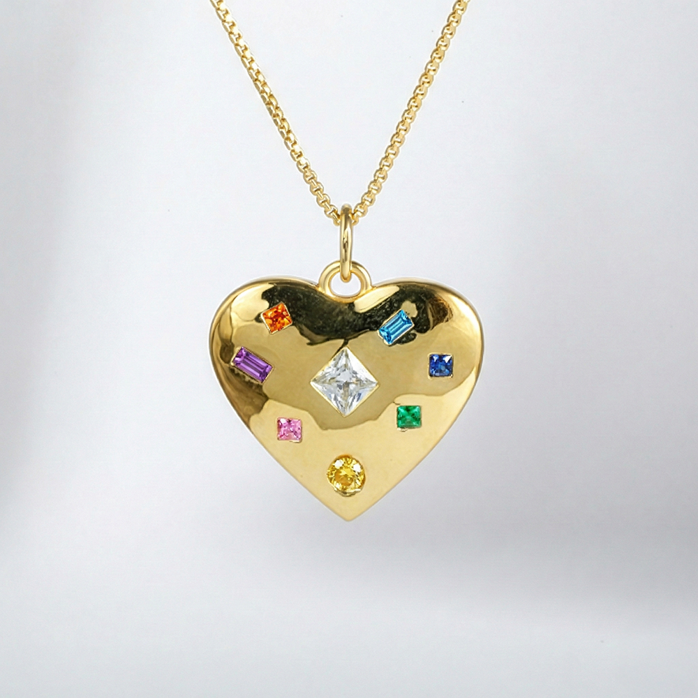 Gold heart-shaped pendant with colorful gemstones on a gold chain against a light gray background