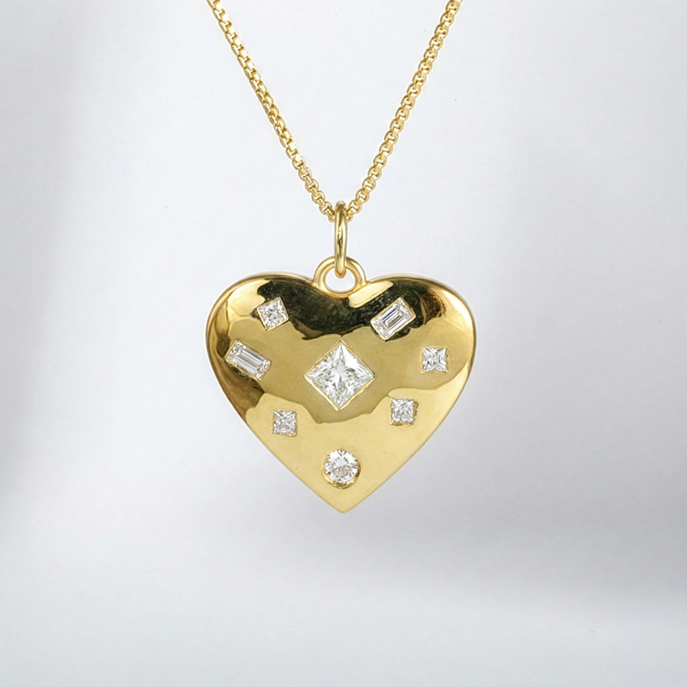 Gold heart-shaped pendant with embedded diamonds on a light gray background