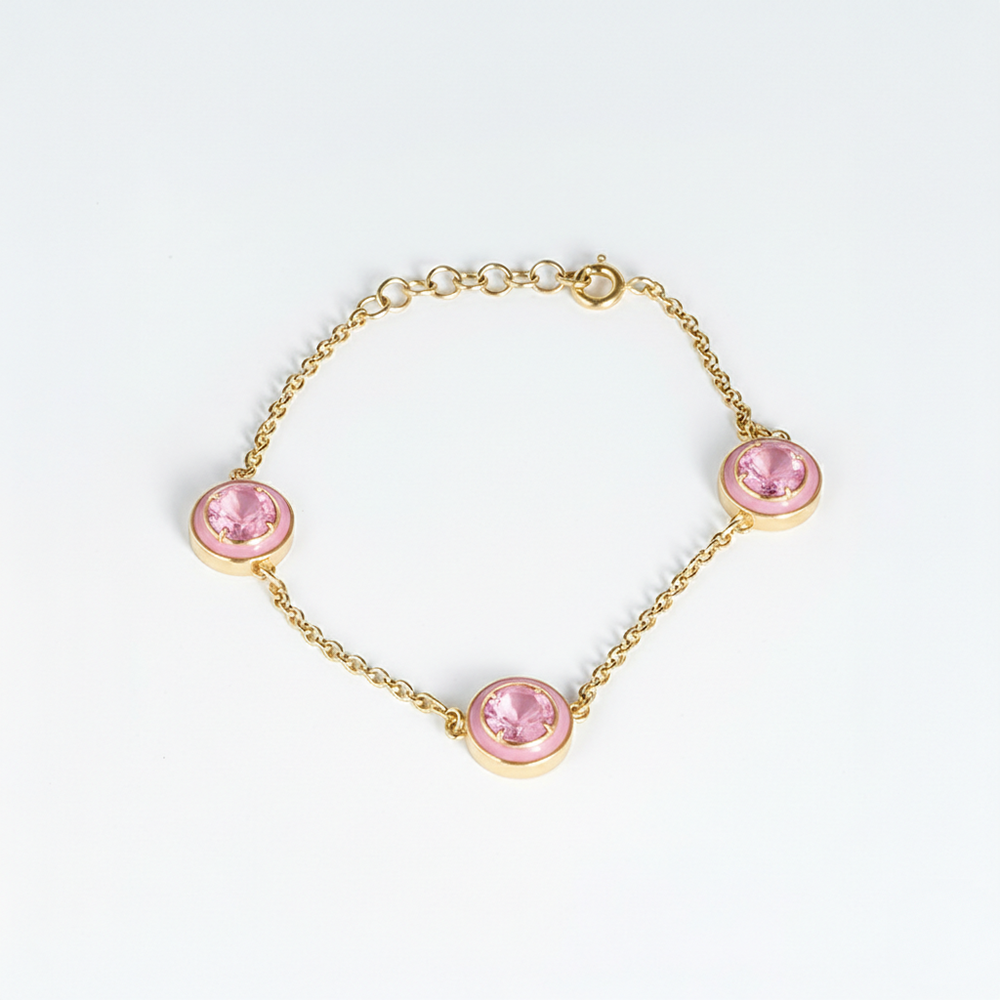 Gold bracelet with pink gemstones on a white background