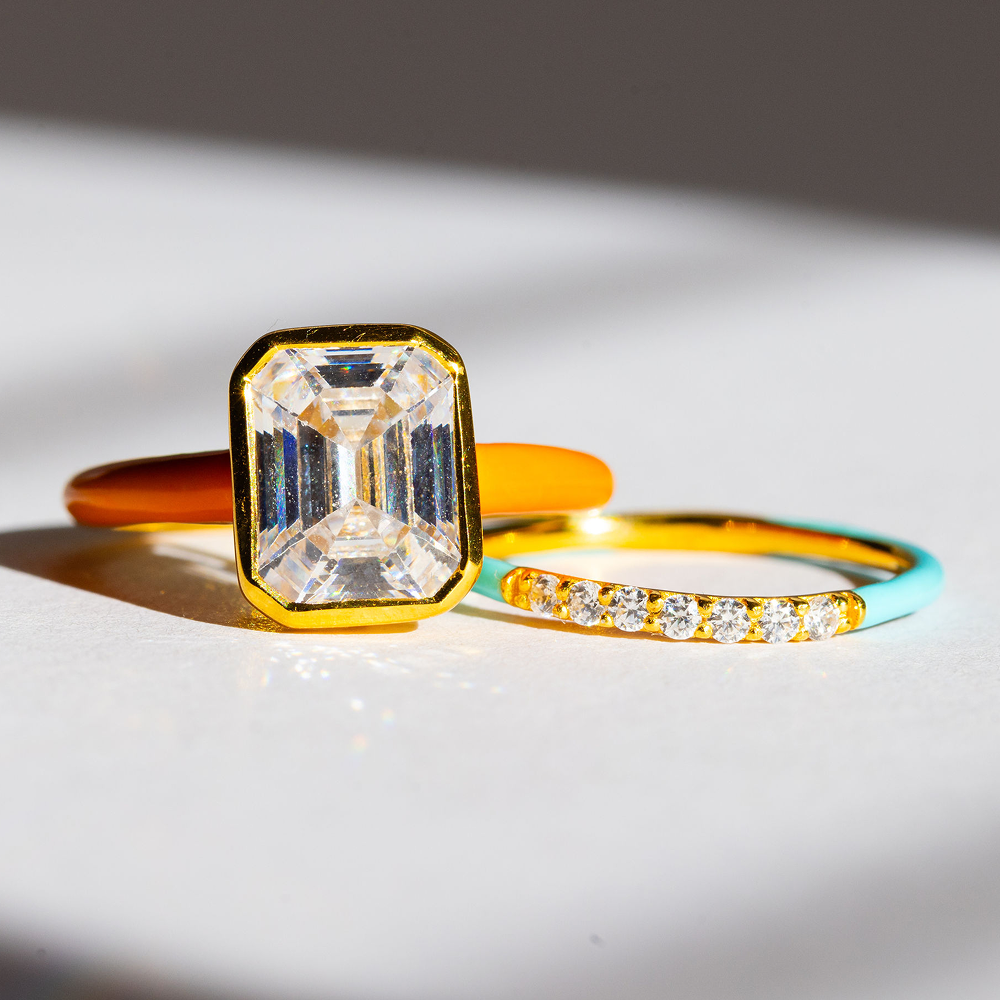 Gold ring with a large rectangular diamond and a smaller ring with a diamond band on a light background
