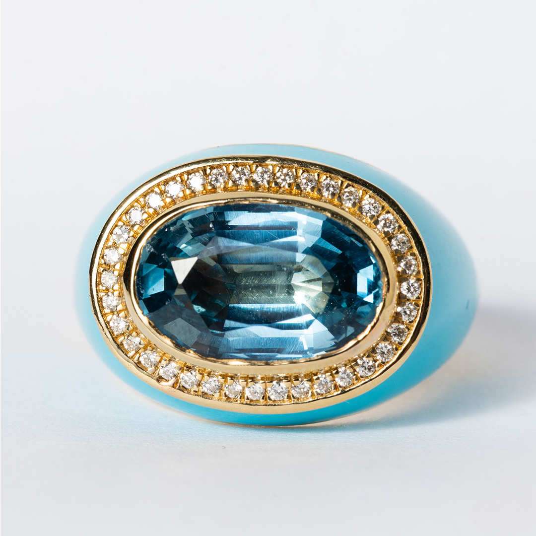 Ring with blue gemstone and gold band on a light gray background
