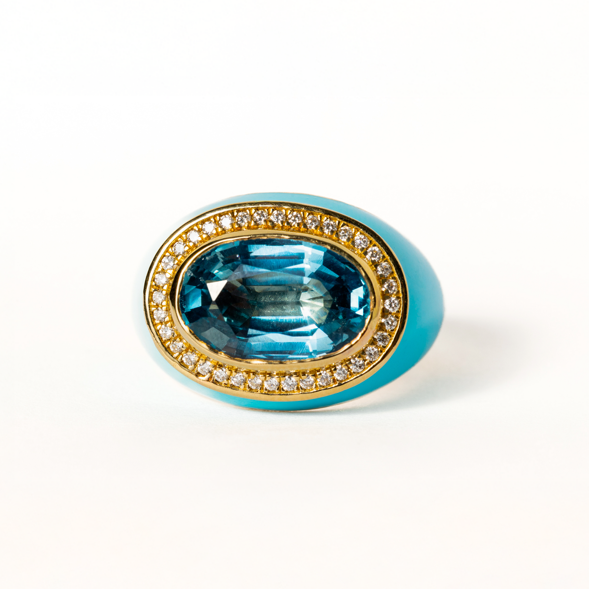 Jewelry ring with blue gemstone and gold band on a white background