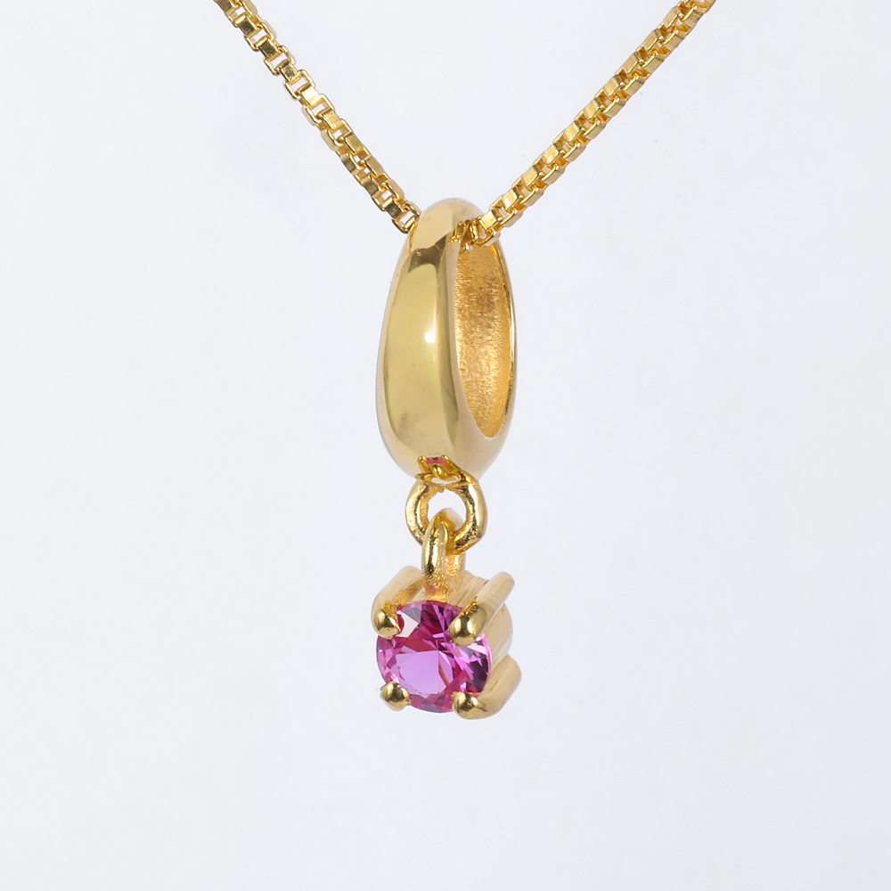 Gold necklace with a pink gemstone pendant on a white background