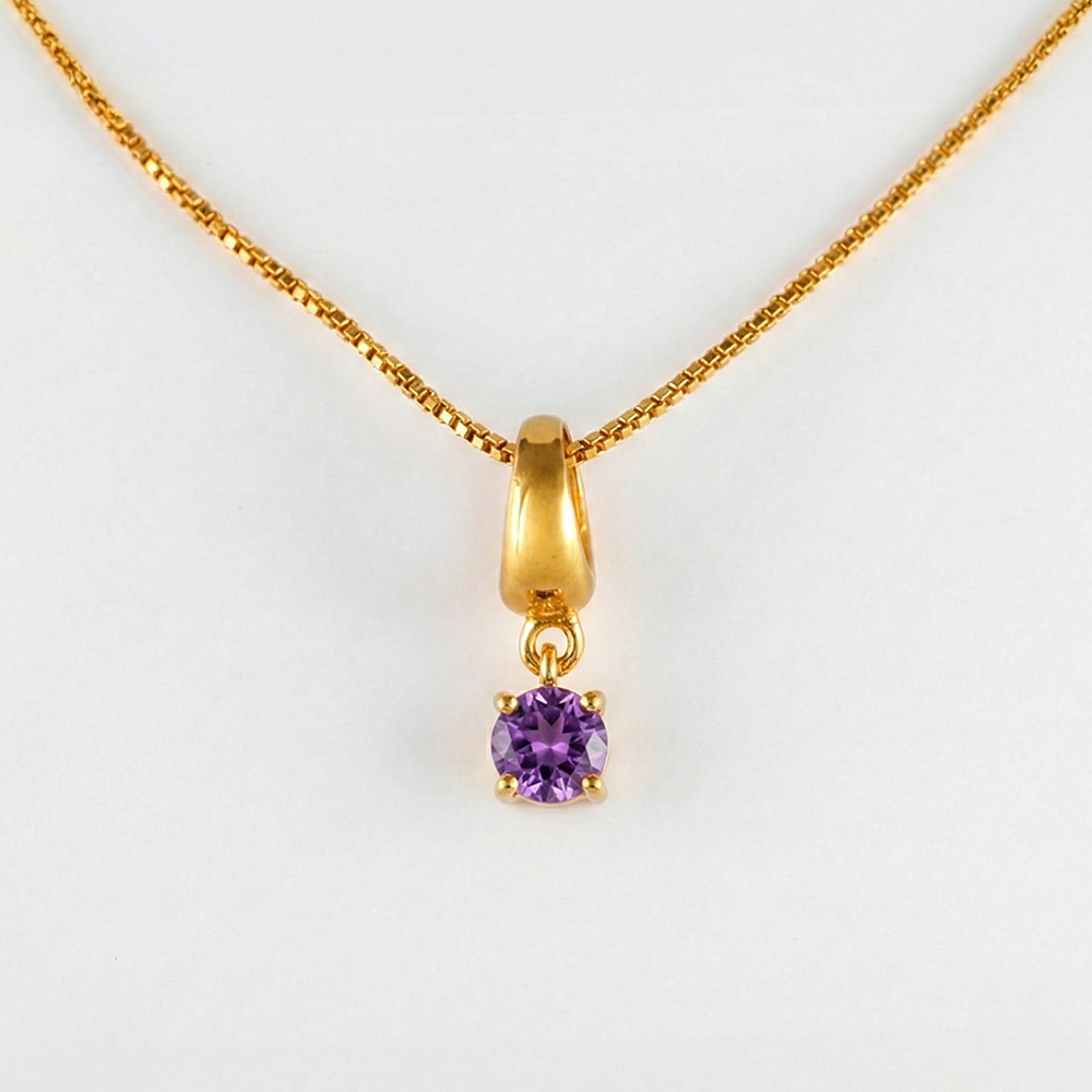 Gold necklace with a purple gemstone pendant on a white background