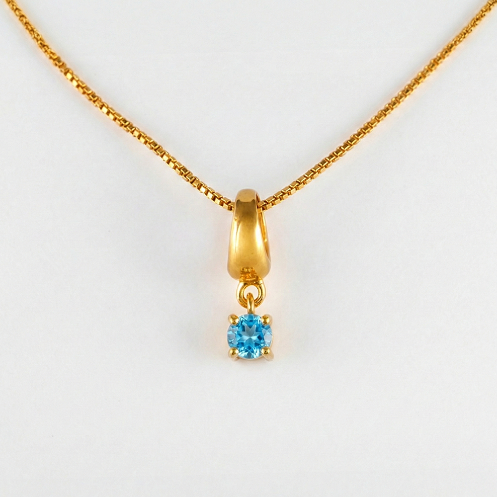 Gold necklace with a blue gemstone pendant on a white background