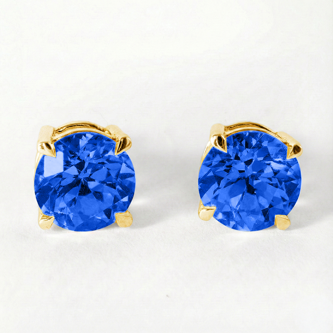 Gold earrings with blue gemstones on a white background