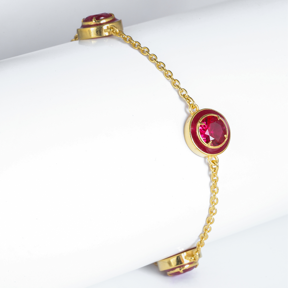 Gold bracelet with red gemstones on a white surface