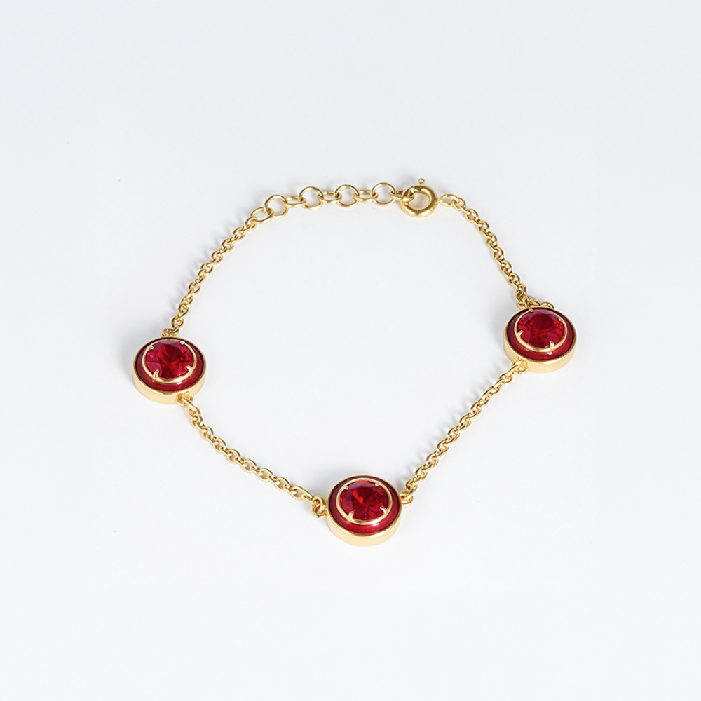 Gold bracelet with red gemstones on a white background