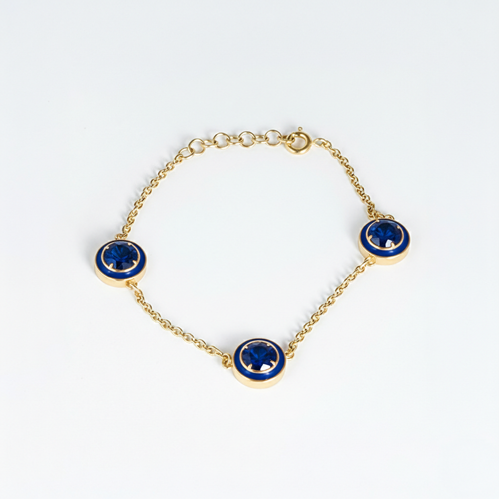 Gold bracelet with blue gemstones on a white background