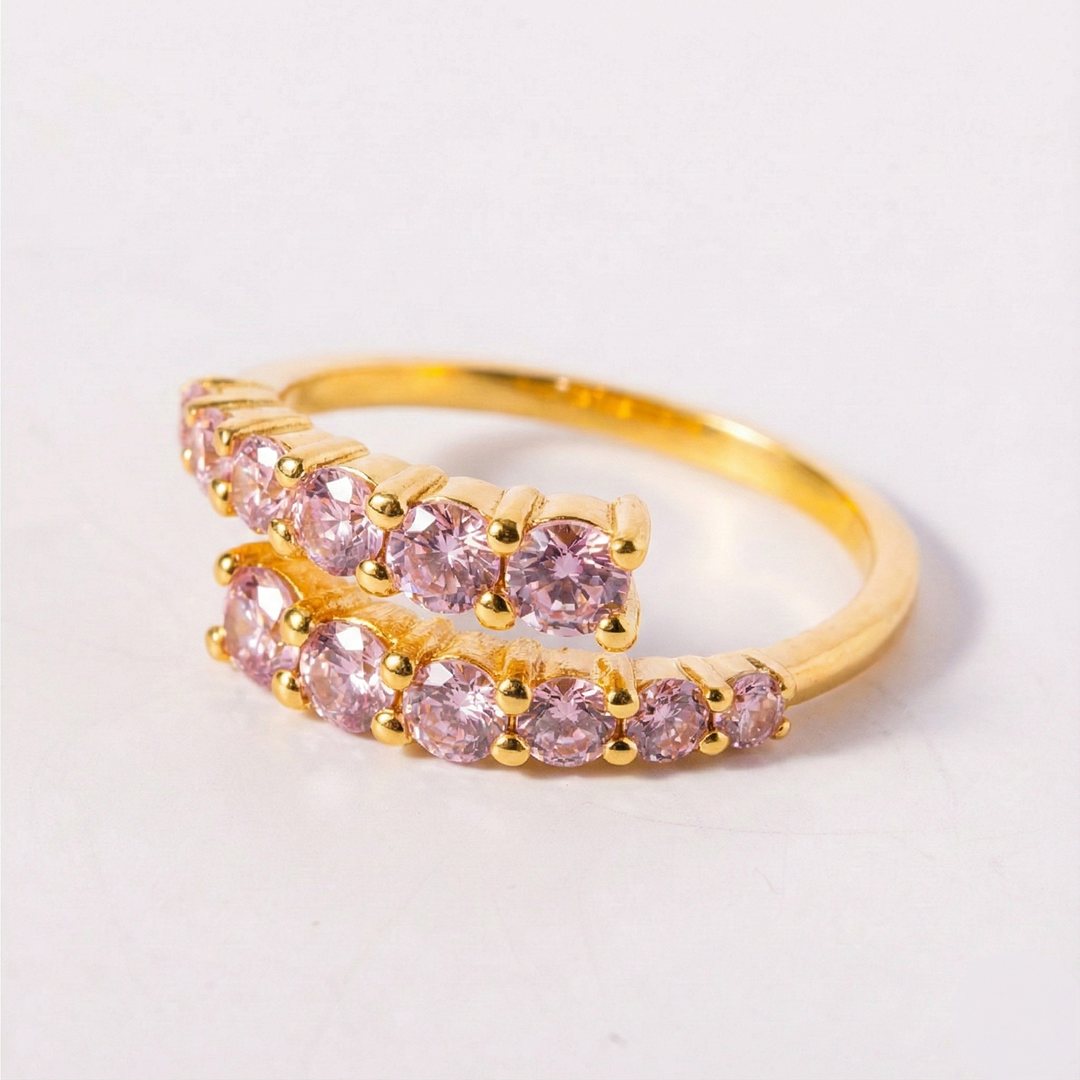 Gold ring with pink gemstones on a light gray background