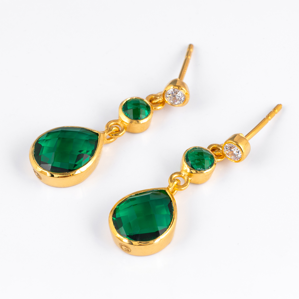 Gold earrings with green gemstones on a white background
