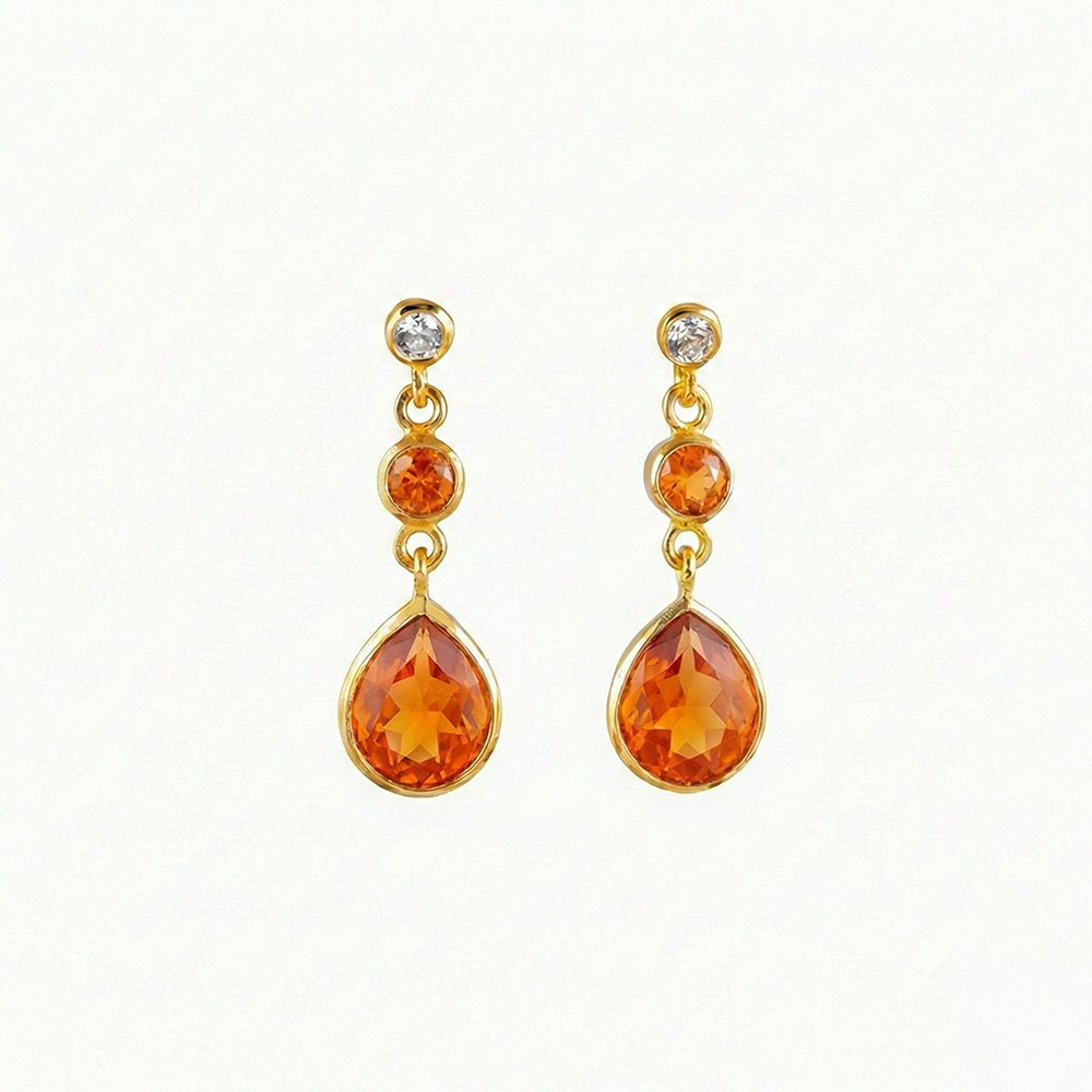 Pair of gold earrings with orange teardrop-shaped gemstones on a white background