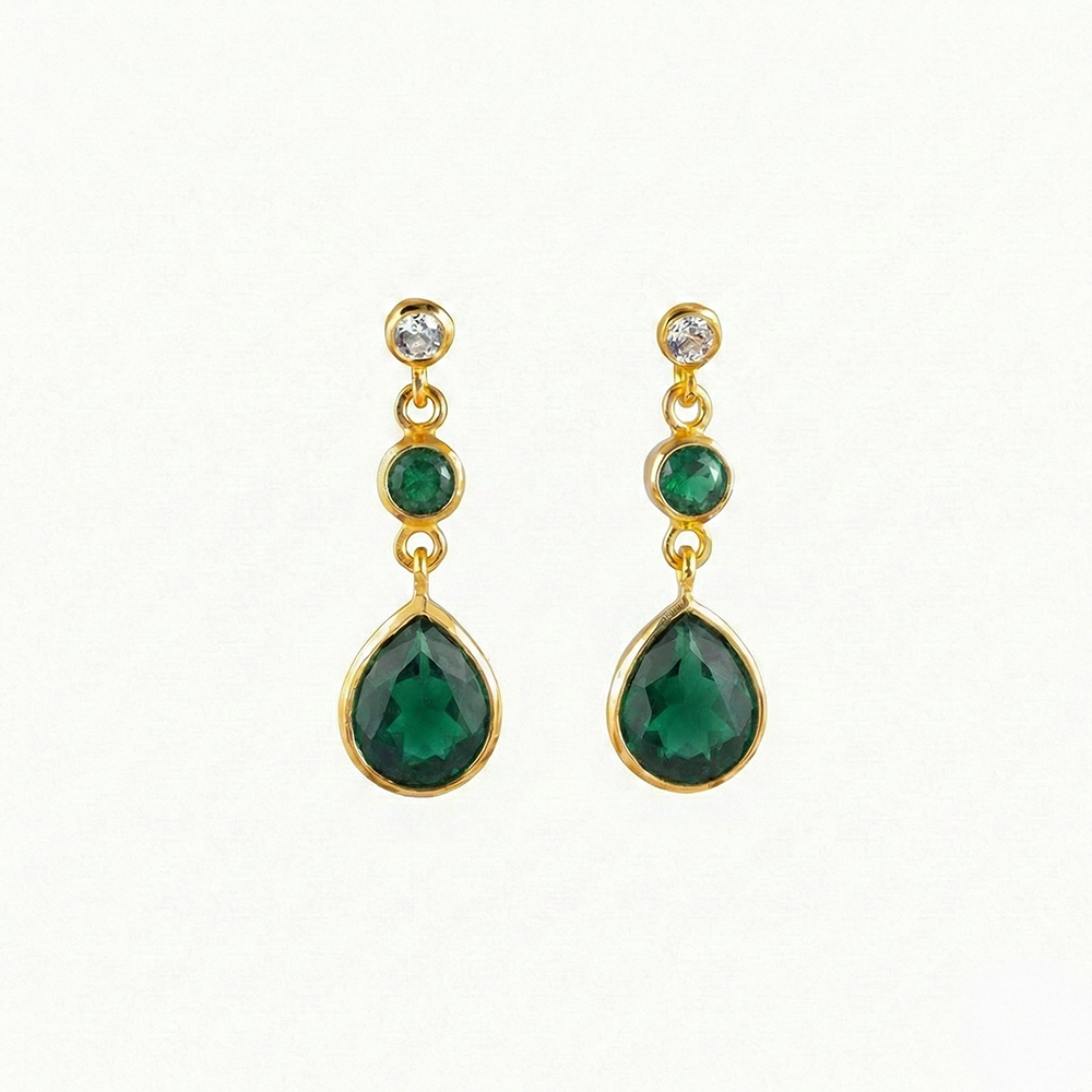 Gold earrings with green gemstones on a white background