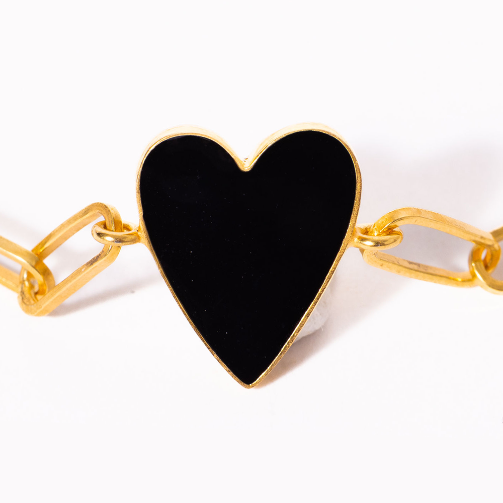 Bracelet with a black heart-shaped charm on a gold chain against a white background