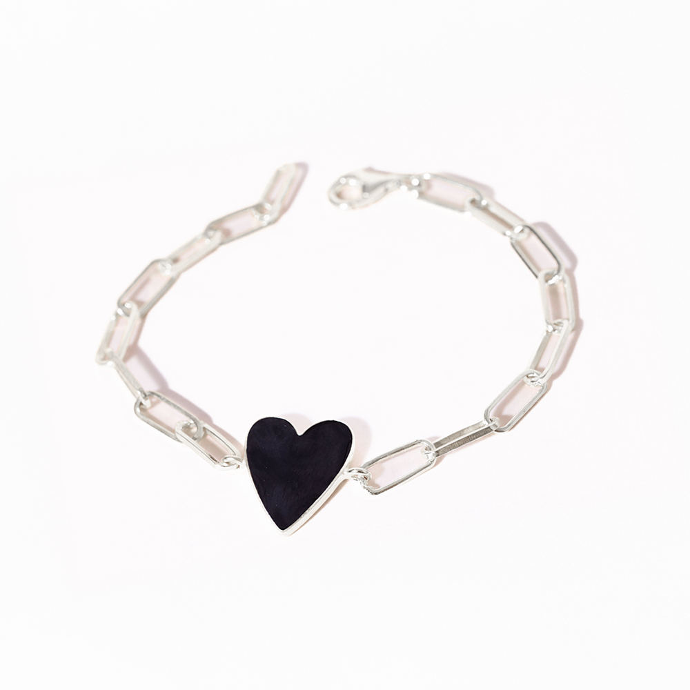 Silver bracelet with a black heart-shaped charm on a white background