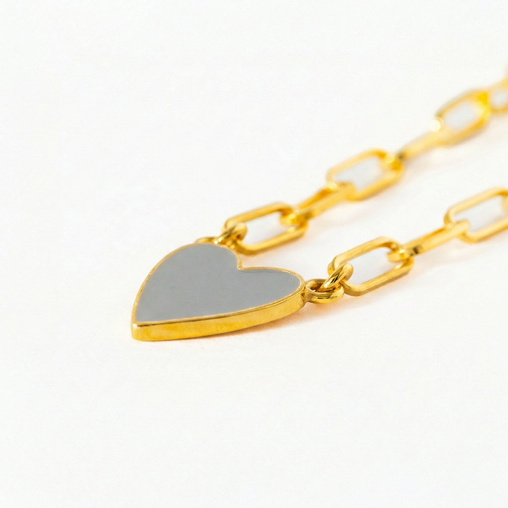 Gold chain bracelet with a heart-shaped pendant on a white background