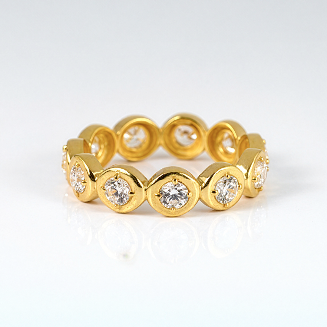 Gold ring with embedded diamonds on a light gray background